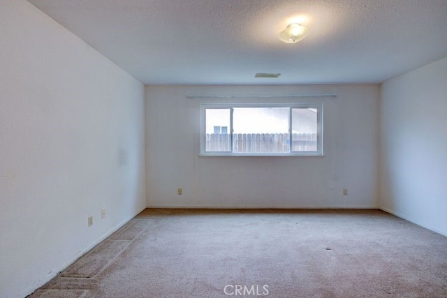 empty room with a textured ceiling, visible vents, and carpet