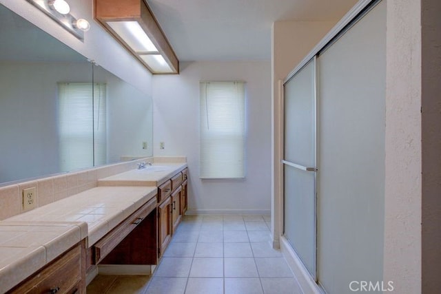 bathroom featuring a shower with door, tile patterned floors, baseboards, and vanity