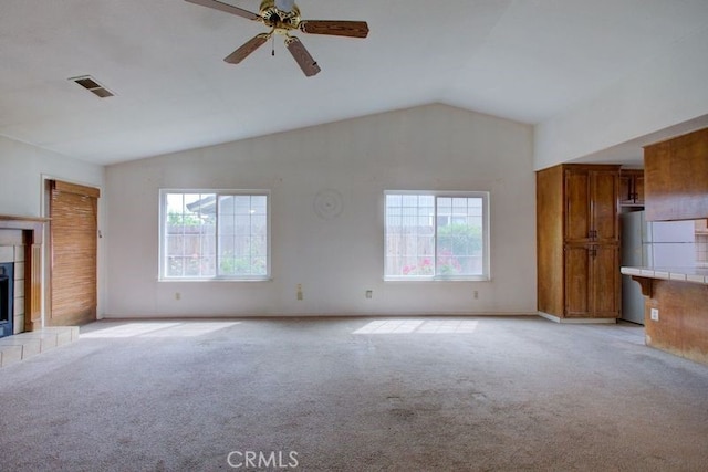 unfurnished living room with light carpet, a healthy amount of sunlight, ceiling fan, and vaulted ceiling