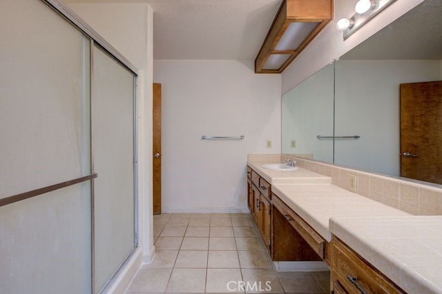 full bathroom featuring a stall shower, tile patterned flooring, vanity, and baseboards