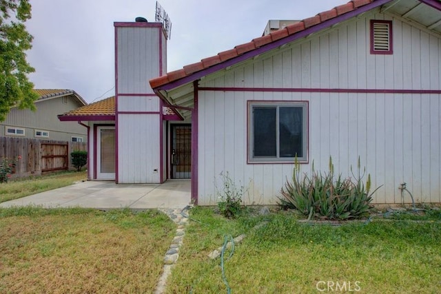 back of house with a lawn, a patio area, a tiled roof, and fence