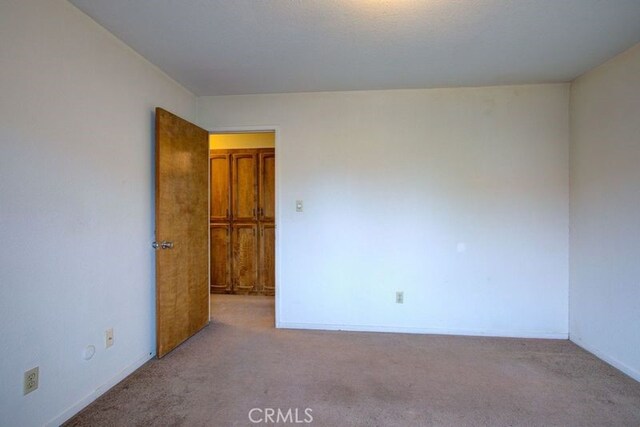 carpeted empty room with baseboards