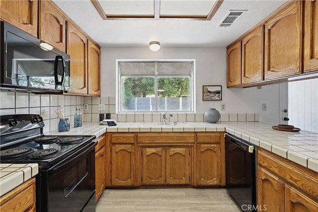 624 Rensselaer Ct, Merced, CA 95348 - kitchen featuring light wood-style flooring, brown cabinetry, visible vents, backsplash, and black appliances