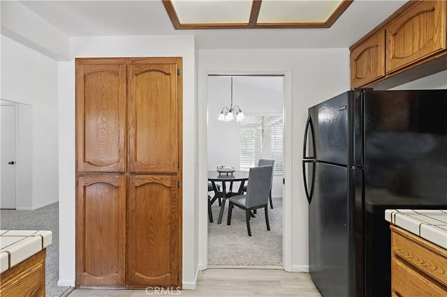 624 Rensselaer Ct, Merced, CA 95348 - kitchen featuring an inviting chandelier, brown cabinets, freestanding refrigerator, light wood-style floors, and tile countertops
