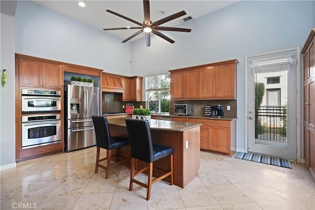 12931 Runway Rd, Playa Vista, CA 90094 - kitchen featuring appliances with stainless steel finishes, a high ceiling, decorative backsplash, a center island, and ceiling fan