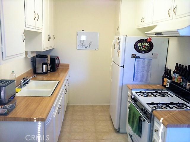 660 S Glassell St Unit 54, Orange, CA 92866 - kitchen with white gas range oven, a sink, wooden counters, under cabinet range hood, and white cabinets