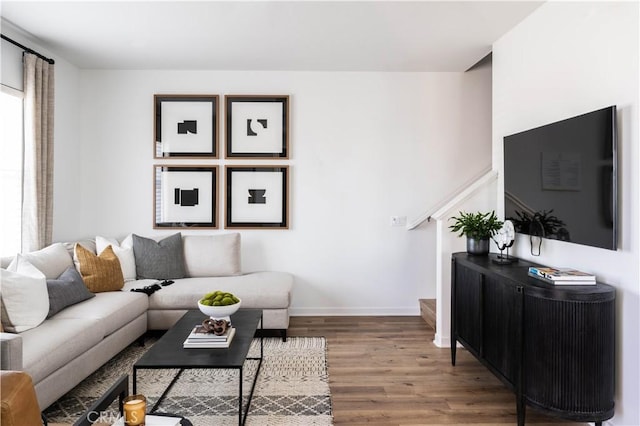 living area with stairs, baseboards, and wood finished floors