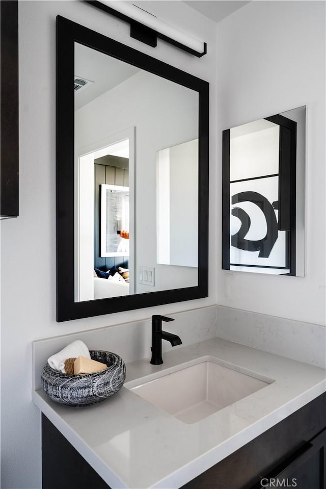 ensuite bathroom with vanity, connected bathroom, and visible vents