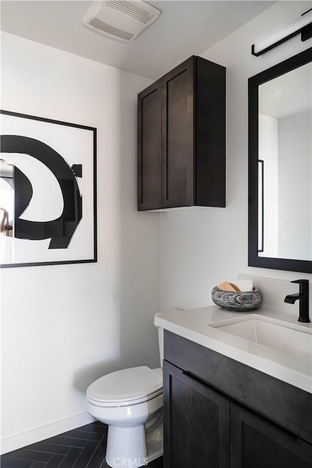 bathroom with vanity, toilet, baseboards, and visible vents