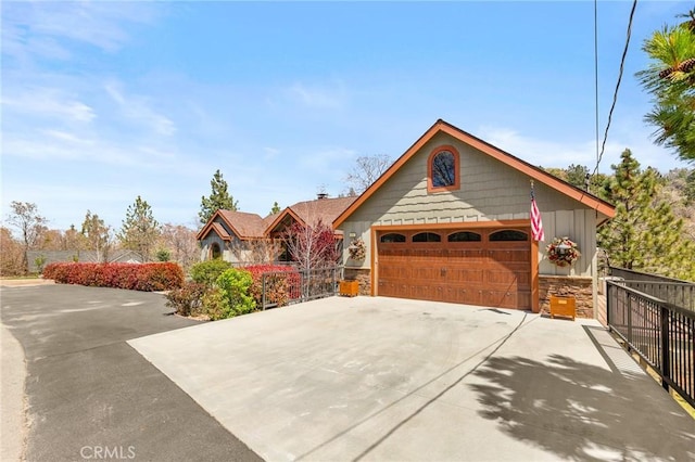 1405 Rock Ridge Dr, Lake Arrowhead, CA 92352 - view of front of property with board and batten siding, fence, stone siding, and driveway