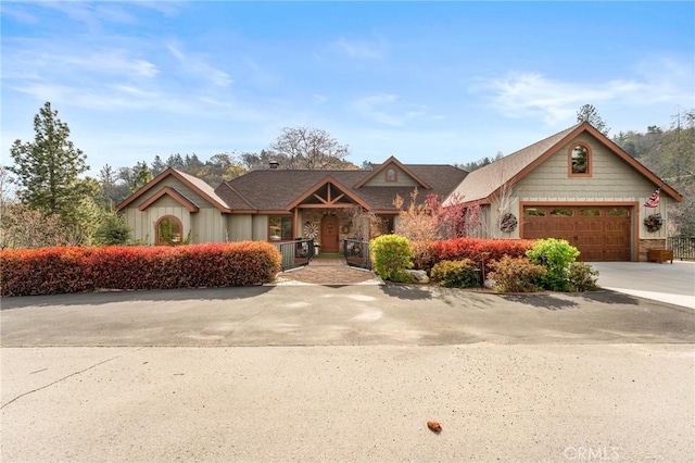 1405 Rock Ridge Dr, Lake Arrowhead, CA 92352 - view of front of house with concrete driveway, a porch, an attached garage, and stone siding