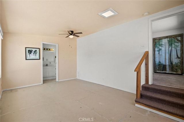 unfurnished room with baseboards, concrete flooring, a ceiling fan, and stairs
