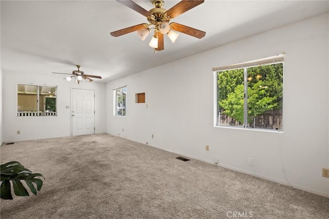 carpeted spare room featuring a ceiling fan, plenty of natural light, and visible vents