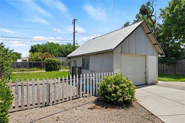 detached garage with concrete driveway and fence