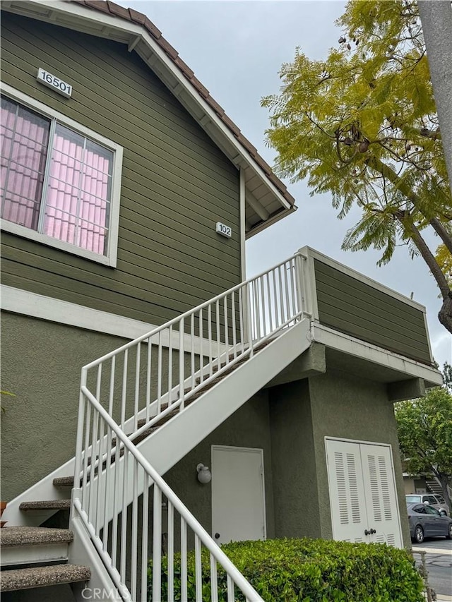 view of side of property featuring stucco siding, stairway, and a balcony