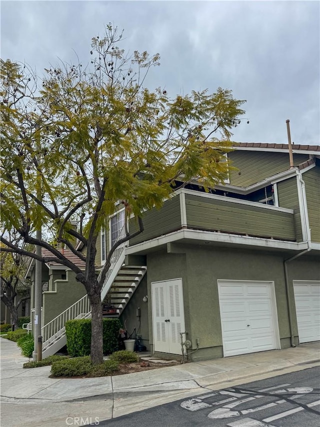 view of front of home with concrete driveway, an attached garage, stucco siding, and a balcony