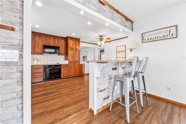 12172 Manley St, Garden Grove, CA 92845 - kitchen with black appliances, a kitchen breakfast bar, brown cabinetry, wood finished floors, and baseboards