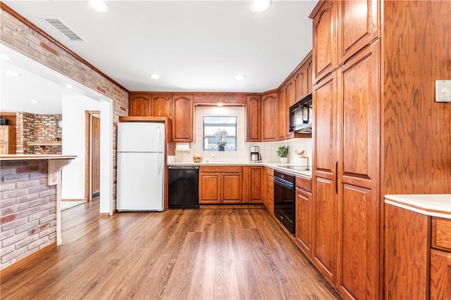 12172 Manley St, Garden Grove, CA 92845 - kitchen featuring black appliances, light wood-style flooring, brown cabinetry, brick wall, and light countertops