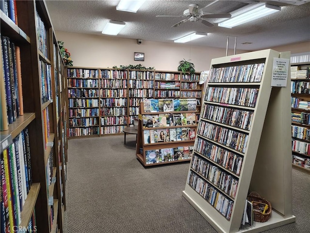 misc room with bookshelves, carpet flooring, ceiling fan, and a textured ceiling
