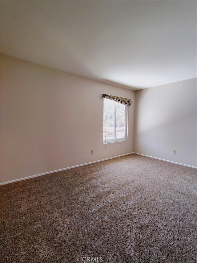 unfurnished room with carpet flooring and baseboards