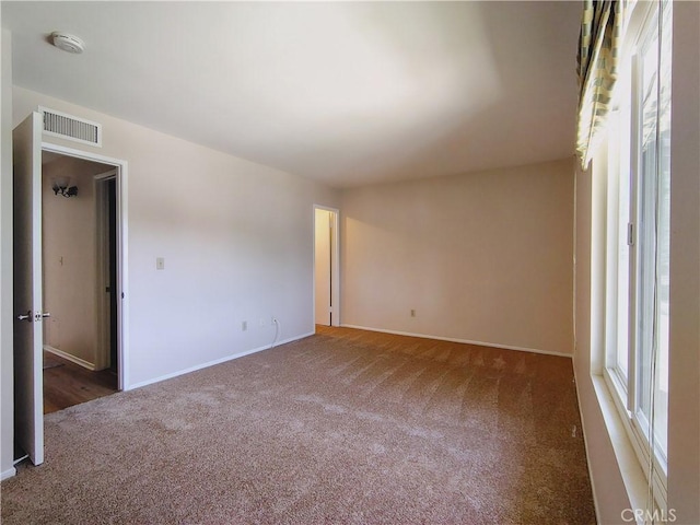 carpeted spare room featuring a smoke detector and baseboards