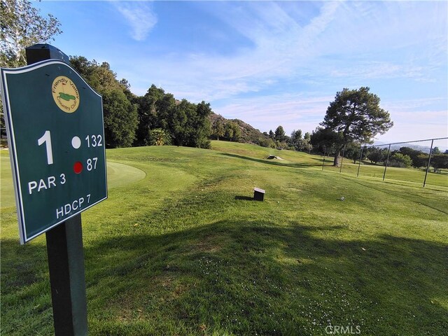 view of property's community featuring view of golf course, a lawn, and view of wooded area