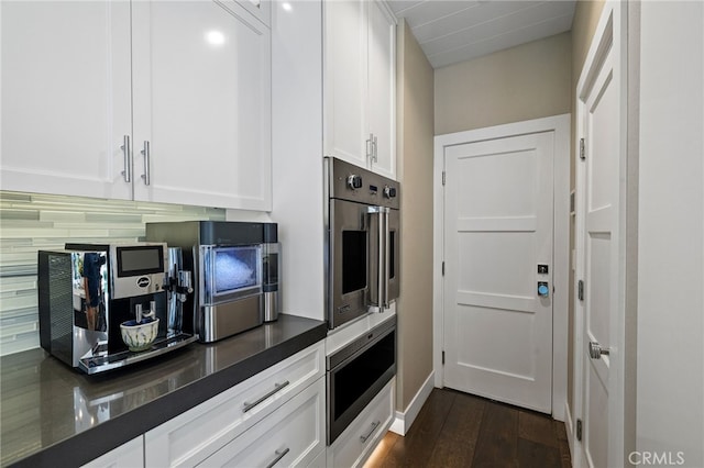 kitchen featuring white cabinetry, dark wood finished floors, stainless steel appliances, and baseboards