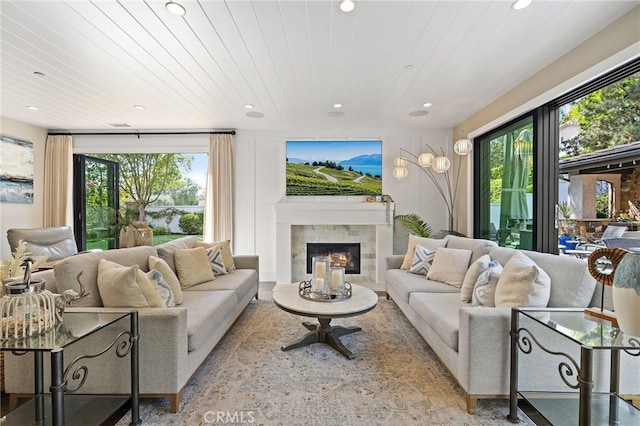 living room with recessed lighting, a glass covered fireplace, and wooden ceiling