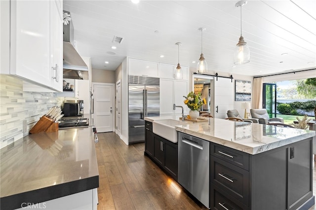 kitchen featuring stainless steel appliances, a sink, white cabinetry, dark cabinetry, and recessed lighting