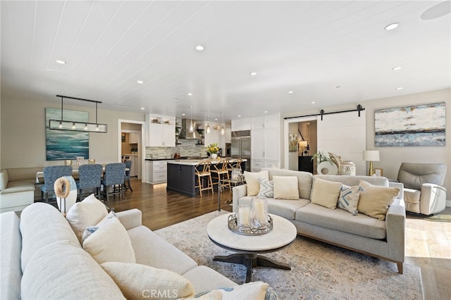 living room with a barn door, recessed lighting, and wood finished floors