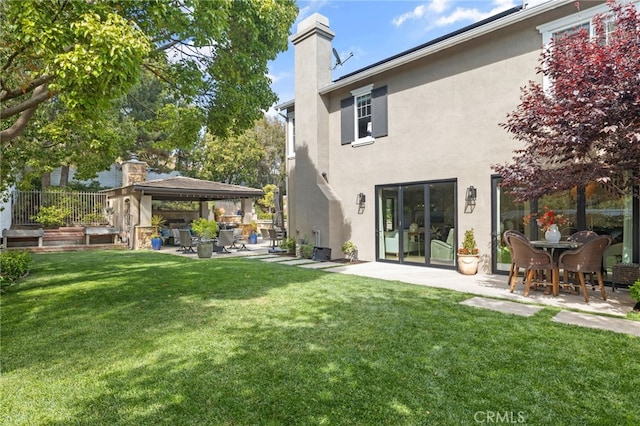 back of house featuring a gazebo, stucco siding, a patio, and a chimney