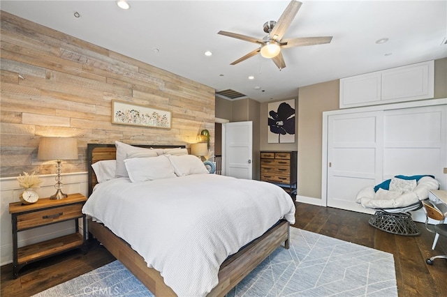 bedroom with wood walls, recessed lighting, baseboards, wood finished floors, and a closet