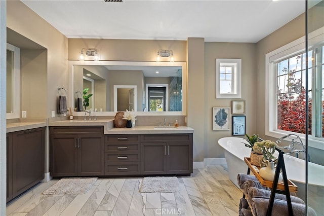 bathroom with a freestanding tub, double vanity, and marble look tile flooring