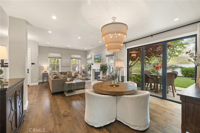 dining area featuring dark wood finished floors, recessed lighting, baseboards, and a lit fireplace