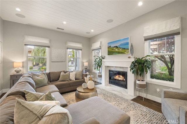 living area featuring recessed lighting, a premium fireplace, baseboards, wood finished floors, and wood ceiling