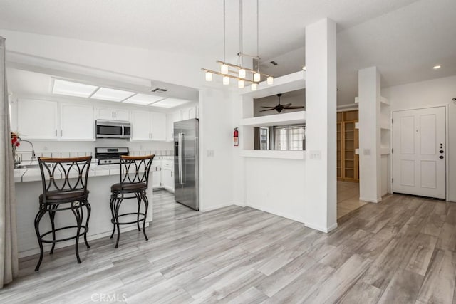25283 Menominee Ct, Moreno Valley, CA 92553 - kitchen featuring a peninsula, stainless steel appliances, a breakfast bar area, ceiling fan, and light wood finished floors