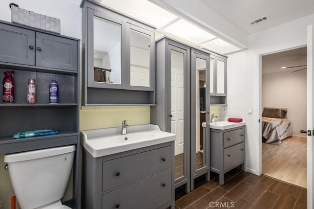 25283 Menominee Ct, Moreno Valley, CA 92553 - bathroom with a sink, toilet, wood finished floors, visible vents, and two vanities