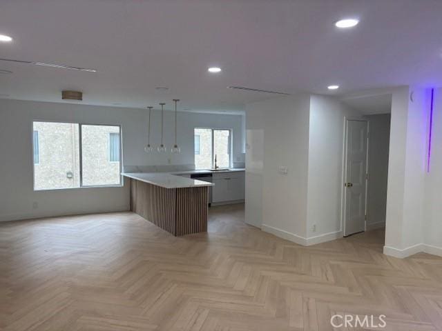 kitchen featuring a peninsula, a sink, baseboards, light countertops, and recessed lighting