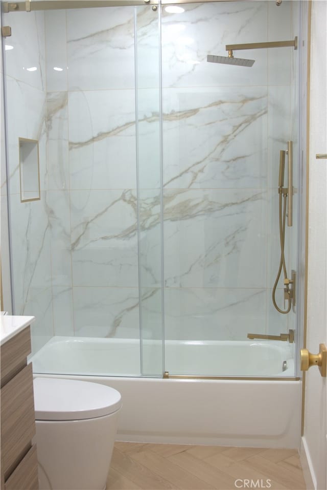 full bath with toilet, vanity, and shower / bath combination with glass door