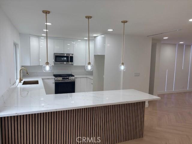 kitchen featuring a sink, a peninsula, stainless steel appliances, and white cabinetry
