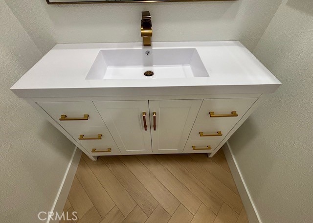 details featuring vanity, baseboards, and wood finished floors