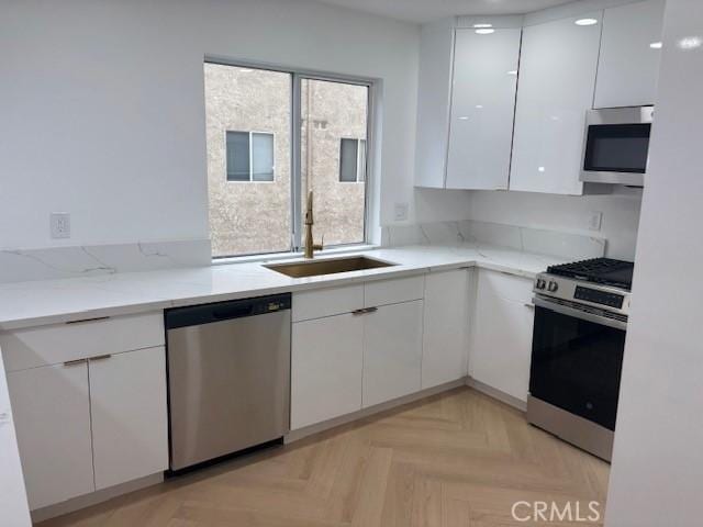 kitchen with white cabinetry, modern cabinets, appliances with stainless steel finishes, and a sink