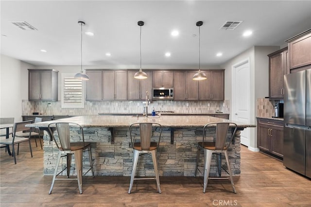 22811 Rolling Brook Ln, Wildomar, CA 92595 - kitchen with appliances with stainless steel finishes, a kitchen breakfast bar, a center island with sink, light stone counters, and tasteful backsplash