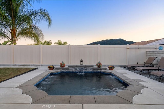 22811 Rolling Brook Ln, Wildomar, CA 92595 - pool at dusk with a mountain view, a fenced backyard, and a patio area