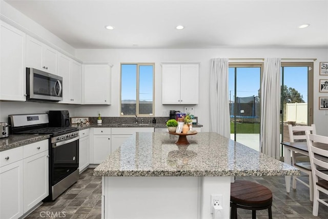 4872 Goldfinch St, Hemet, CA 92545 - kitchen with stainless steel appliances, a sink, a breakfast bar area, a center island, and white cabinets