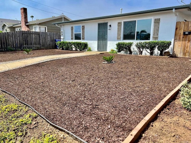 ranch-style house featuring stucco siding and fence