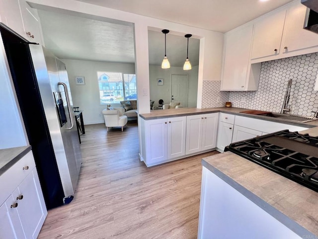 kitchen with white cabinets, stainless steel fridge, light wood-style flooring, and a sink