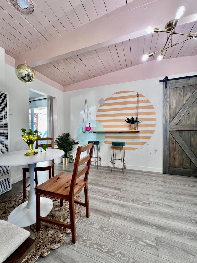 dining room with a heating unit, beam ceiling, a barn door, and wood finished floors