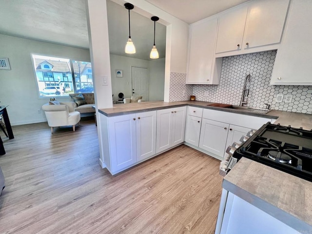 kitchen featuring white cabinetry, backsplash, light wood-style flooring, and a sink