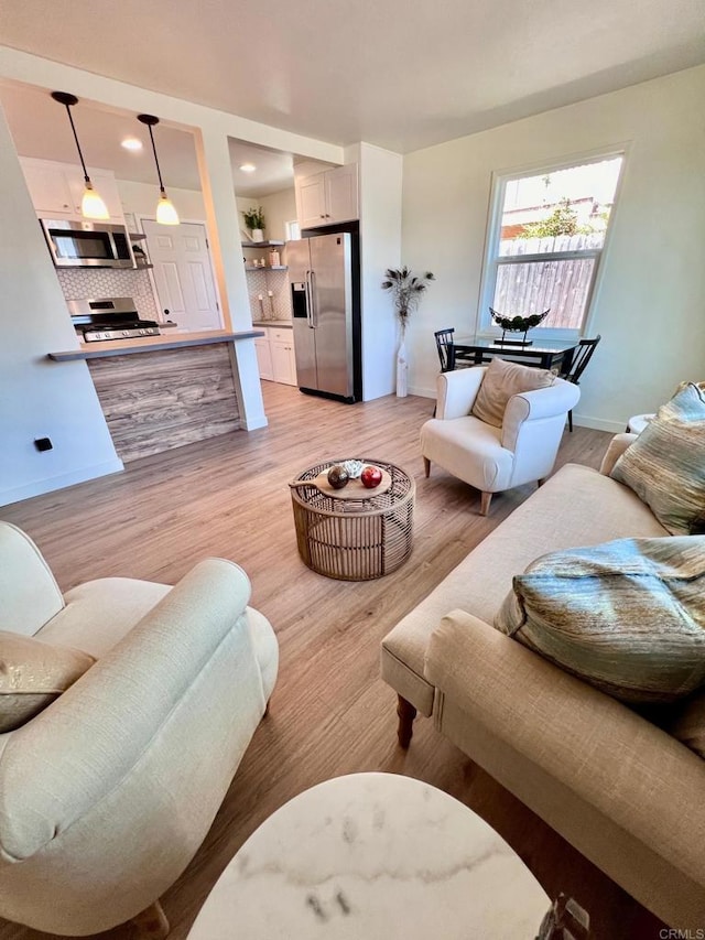 living area with baseboards, light wood-style flooring, and recessed lighting